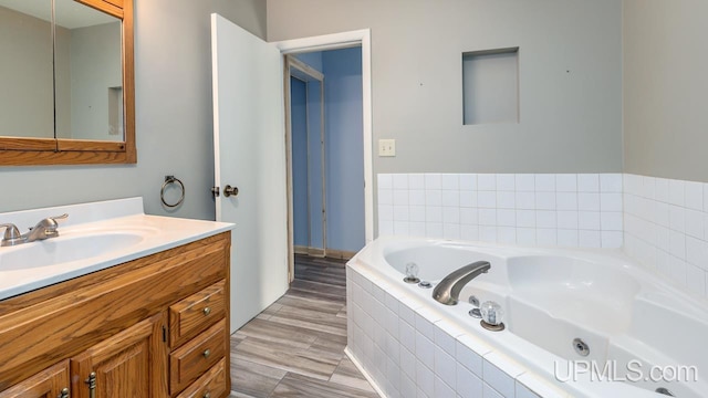 bathroom with tiled tub, vanity, and hardwood / wood-style flooring