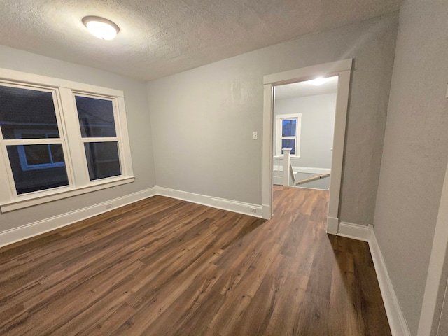 unfurnished room featuring dark hardwood / wood-style floors and a textured ceiling