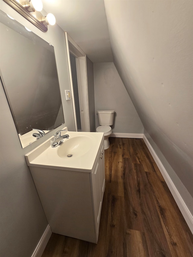 bathroom with hardwood / wood-style floors, vanity, toilet, and lofted ceiling