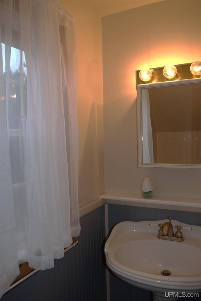 bathroom featuring wooden walls and sink