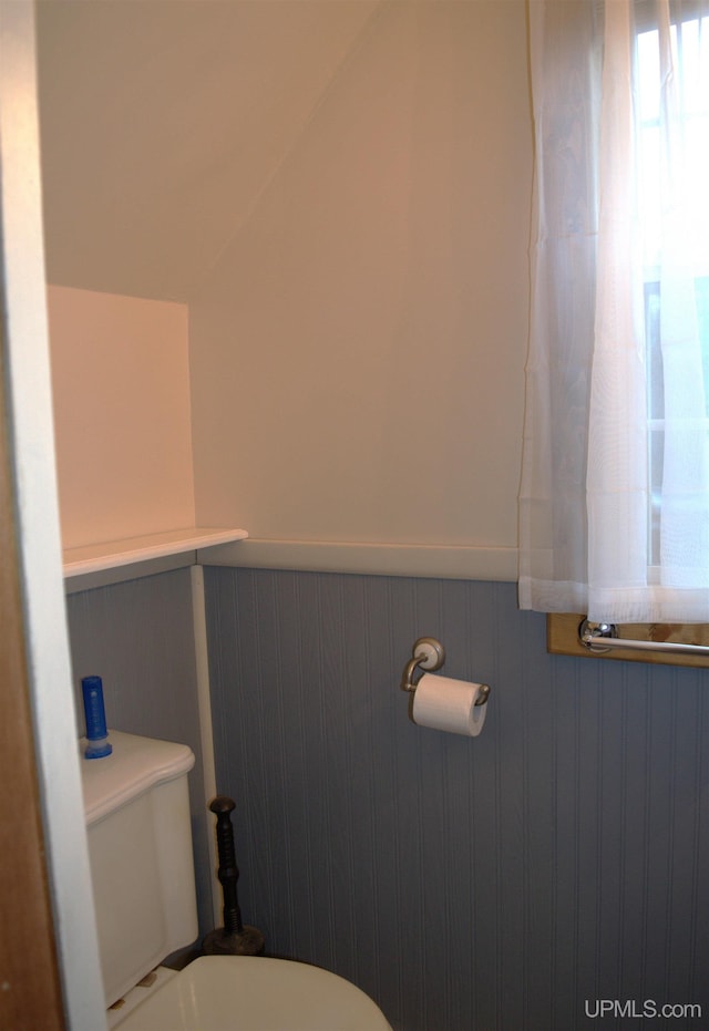 bathroom with wood walls and toilet