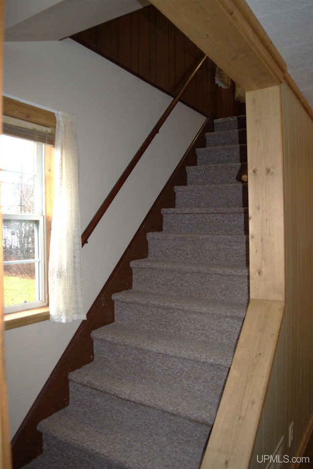 stairway featuring wooden walls and vaulted ceiling