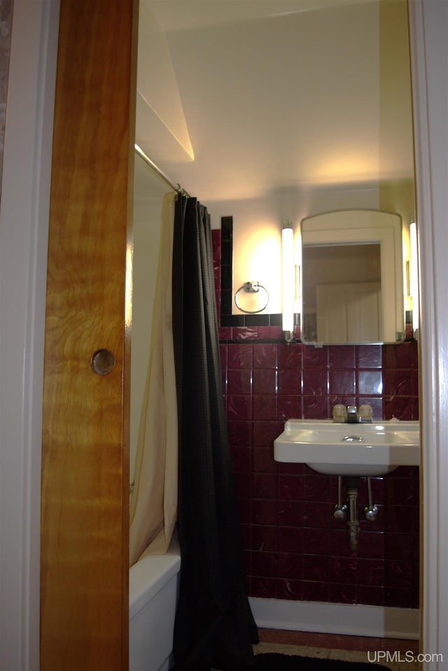 bathroom with sink, tile walls, and shower / tub combo with curtain