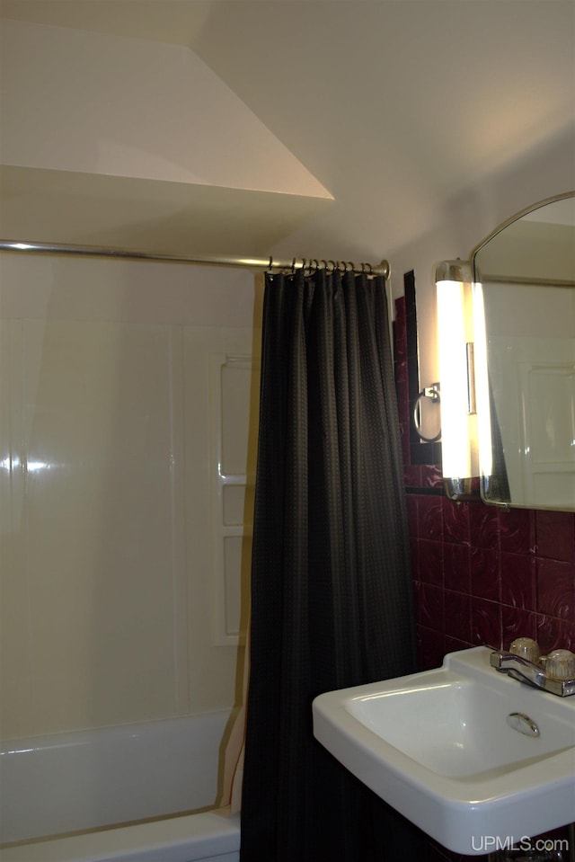 bathroom with tasteful backsplash, sink, and shower / bath combination with curtain