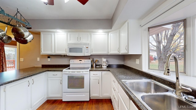 kitchen with sink, dark hardwood / wood-style flooring, kitchen peninsula, white appliances, and white cabinets