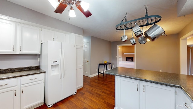 kitchen with white cabinetry, white fridge with ice dispenser, ceiling fan, dark hardwood / wood-style floors, and kitchen peninsula