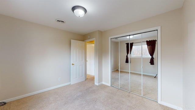 unfurnished bedroom featuring light colored carpet and a closet