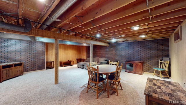 dining space featuring light carpet and brick wall