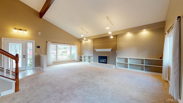 unfurnished living room featuring beam ceiling, a tile fireplace, light carpet, and high vaulted ceiling