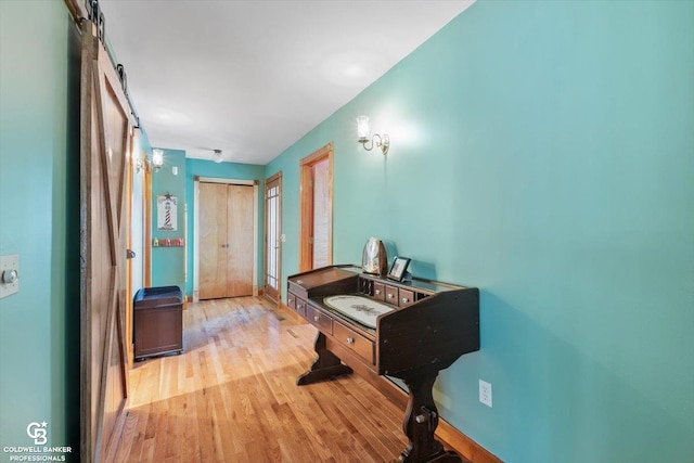 hallway with a barn door and light wood-type flooring