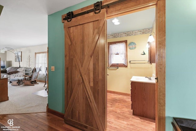 hall with a barn door, light hardwood / wood-style flooring, and sink