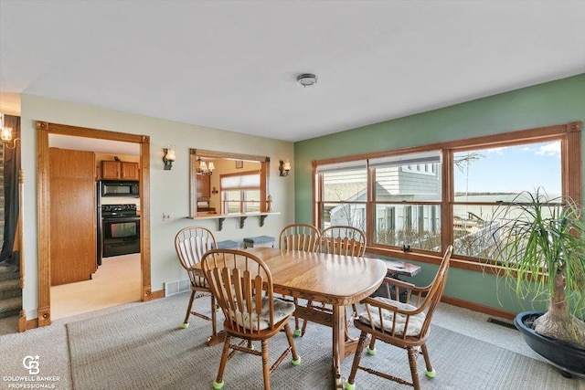 carpeted dining area featuring a notable chandelier and a water view