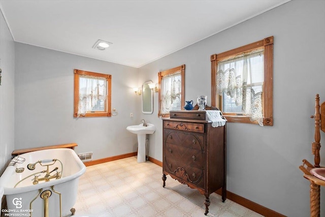 bathroom featuring a tub to relax in, a wealth of natural light, and sink