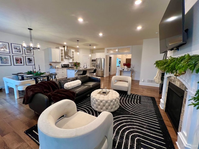 living room with a notable chandelier, sink, and dark wood-type flooring