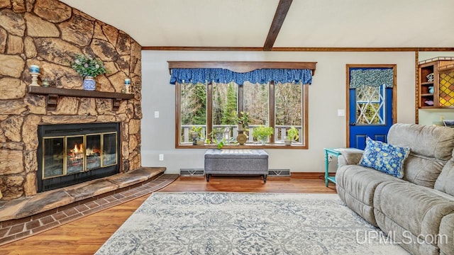 living room featuring hardwood / wood-style flooring, lofted ceiling with beams, ornamental molding, and a fireplace