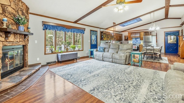 living room featuring a fireplace, ceiling fan, vaulted ceiling with skylight, and hardwood / wood-style floors