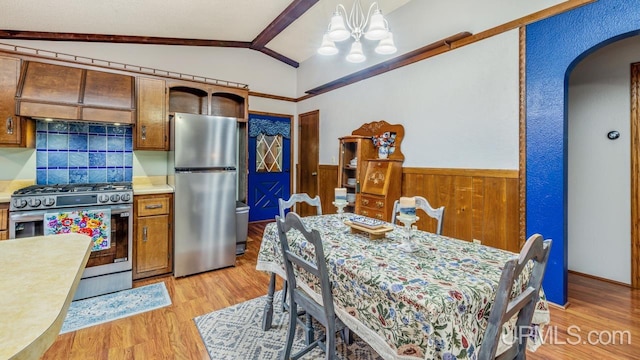 dining room with wooden walls, light hardwood / wood-style floors, lofted ceiling, and a notable chandelier