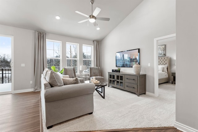 living room with ceiling fan, plenty of natural light, high vaulted ceiling, and light wood-type flooring