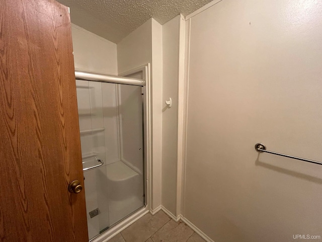 bathroom featuring tile patterned floors, a shower with door, and a textured ceiling