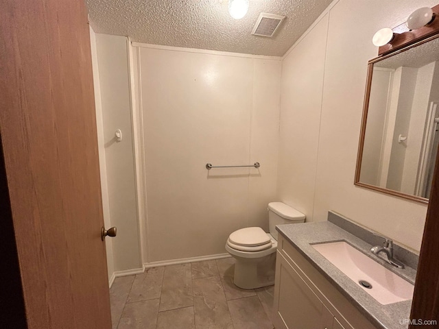 bathroom with vanity, toilet, and a textured ceiling