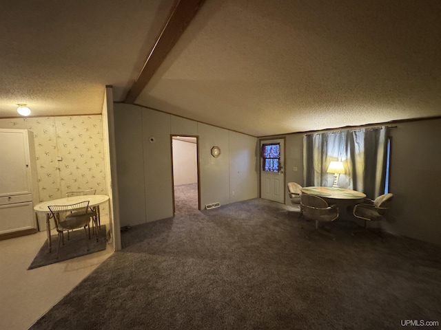 interior space with dark colored carpet, vaulted ceiling with beams, and a textured ceiling