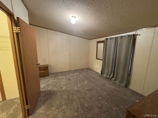 interior space featuring dark colored carpet and a textured ceiling