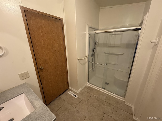 bathroom featuring tile patterned flooring, a shower with shower door, and sink