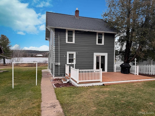 rear view of house featuring a wooden deck and a yard