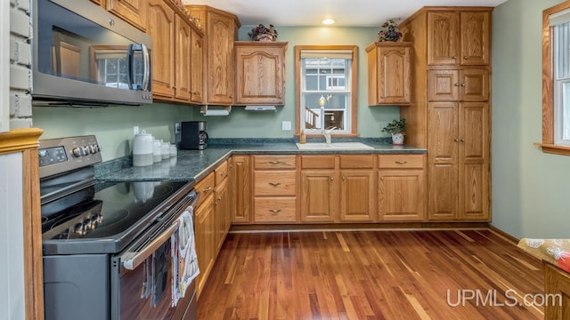 kitchen with dark stone countertops, sink, dark wood-type flooring, and appliances with stainless steel finishes