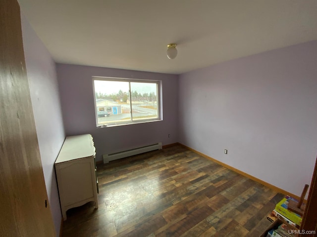 empty room with dark wood-type flooring and a baseboard heating unit