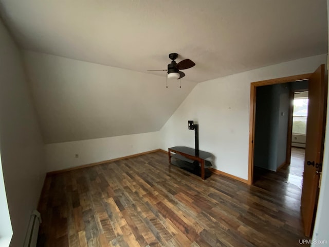 additional living space with lofted ceiling, ceiling fan, dark hardwood / wood-style floors, and a baseboard heating unit