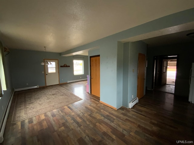 empty room featuring dark hardwood / wood-style floors and a baseboard heating unit