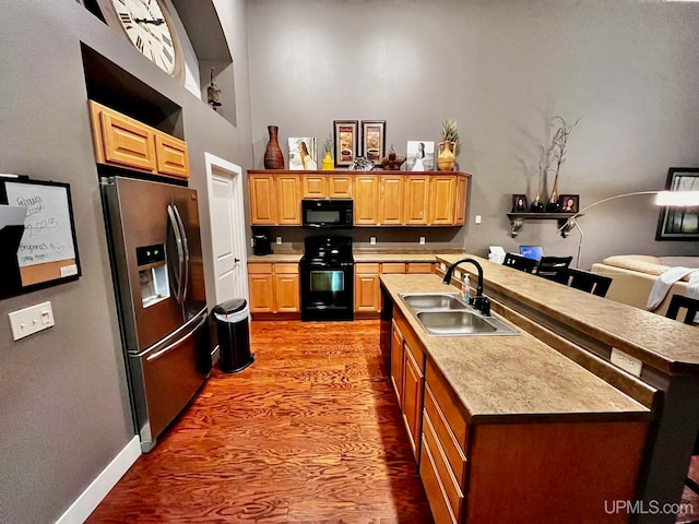 kitchen with sink, black appliances, and a center island with sink