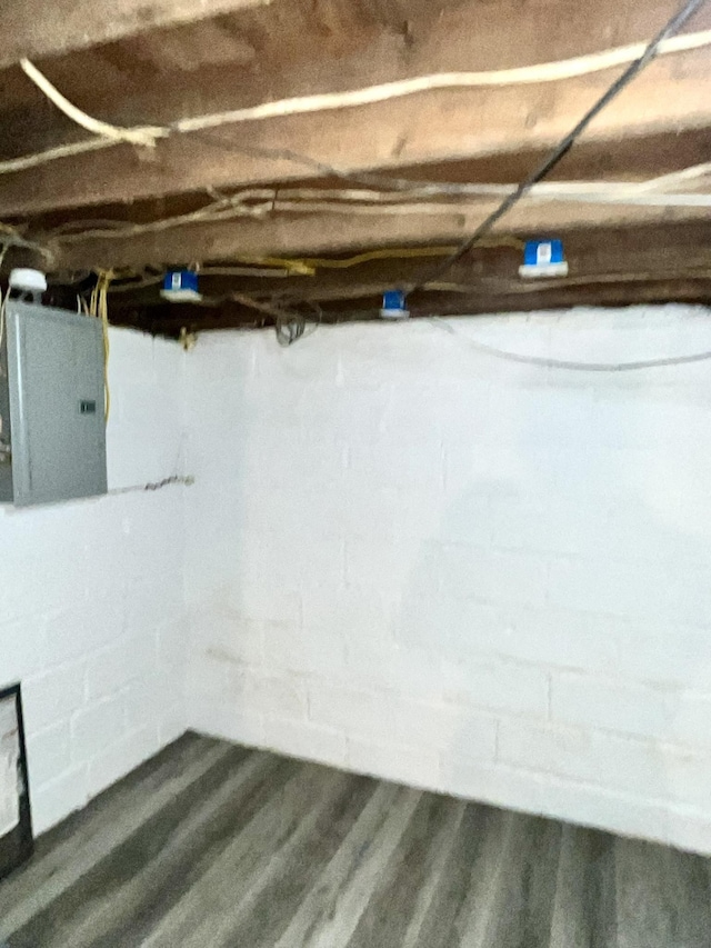 basement with dark wood-type flooring and electric panel