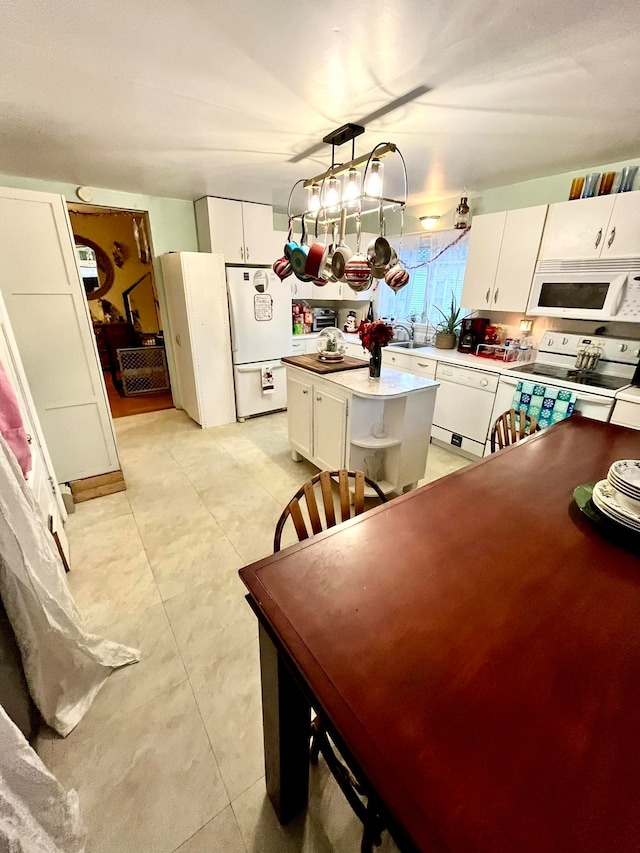 kitchen featuring sink, decorative light fixtures, a kitchen island, white appliances, and white cabinets