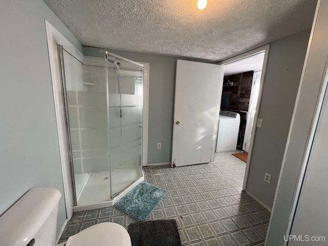 bathroom with a textured ceiling, washer / clothes dryer, toilet, and a shower with door