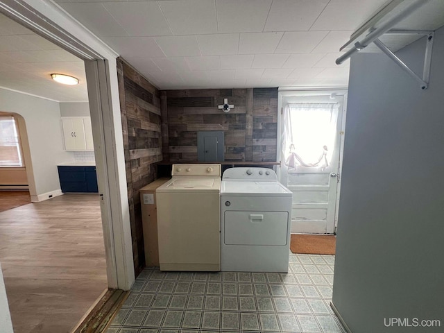 laundry area featuring washer and dryer, a baseboard heating unit, and wooden walls