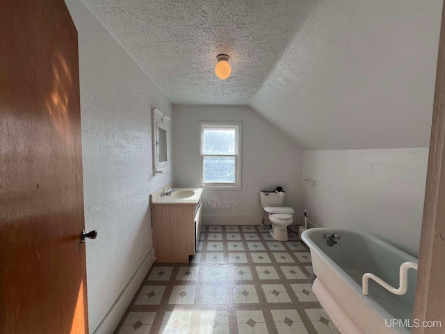 bathroom with vanity, lofted ceiling, a bath, toilet, and a textured ceiling