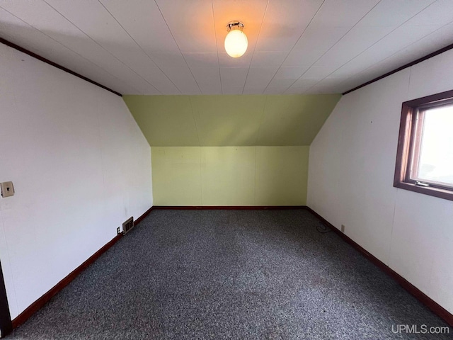 additional living space featuring dark colored carpet and lofted ceiling