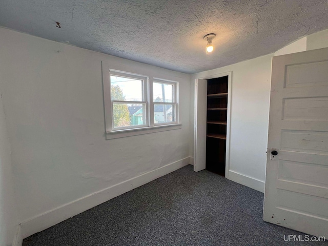 unfurnished bedroom with a closet, dark carpet, and a textured ceiling