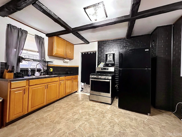 kitchen featuring sink, black fridge, beam ceiling, and stainless steel range with gas stovetop