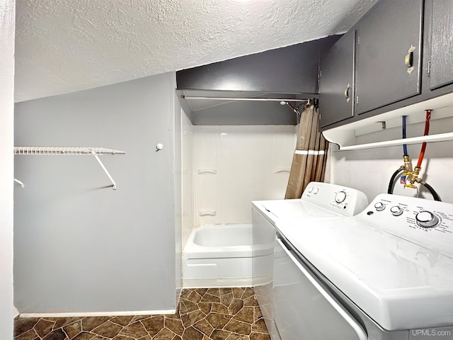 washroom with a textured ceiling, cabinets, and washer and clothes dryer