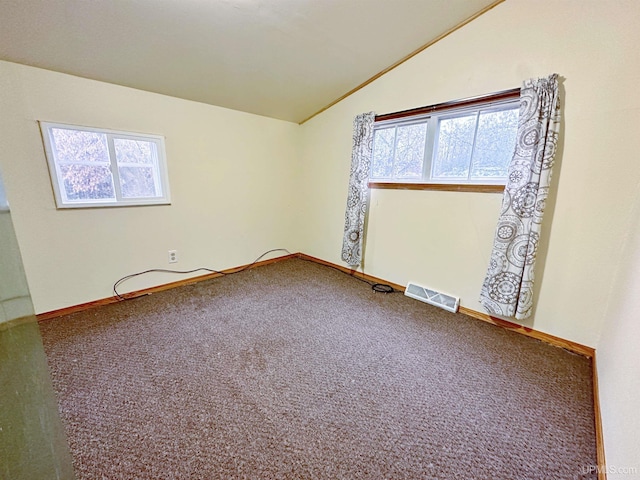 spare room featuring plenty of natural light, carpet, and vaulted ceiling