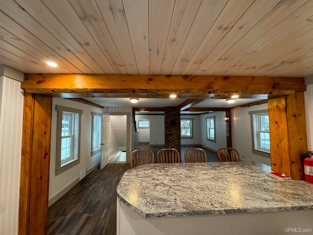 dining room with beam ceiling, dark hardwood / wood-style floors, and wood ceiling