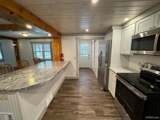 kitchen with a breakfast bar, appliances with stainless steel finishes, light stone counters, and a wealth of natural light