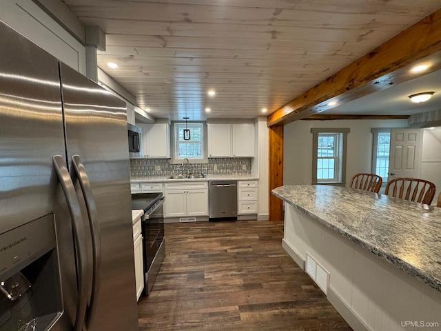 kitchen with appliances with stainless steel finishes, dark hardwood / wood-style flooring, white cabinetry, and plenty of natural light