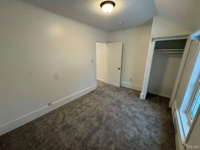 unfurnished bedroom with dark carpet, ornamental molding, a textured ceiling, and a closet