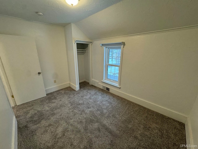 unfurnished bedroom with a closet, carpet floors, a textured ceiling, and vaulted ceiling