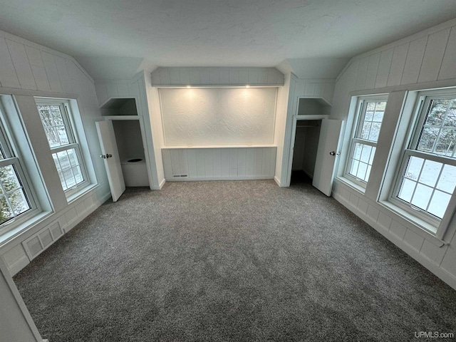 interior space with a textured ceiling, carpet floors, and lofted ceiling