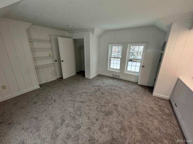 unfurnished bedroom with a textured ceiling, carpet, and vaulted ceiling